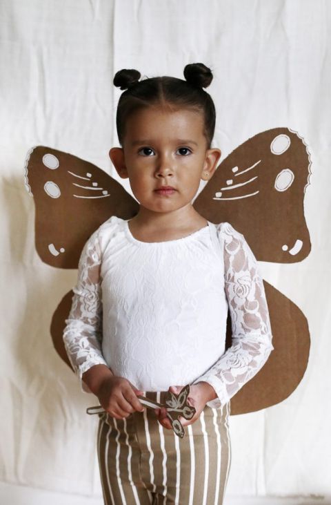 little girl in cardboard moth wings costume
