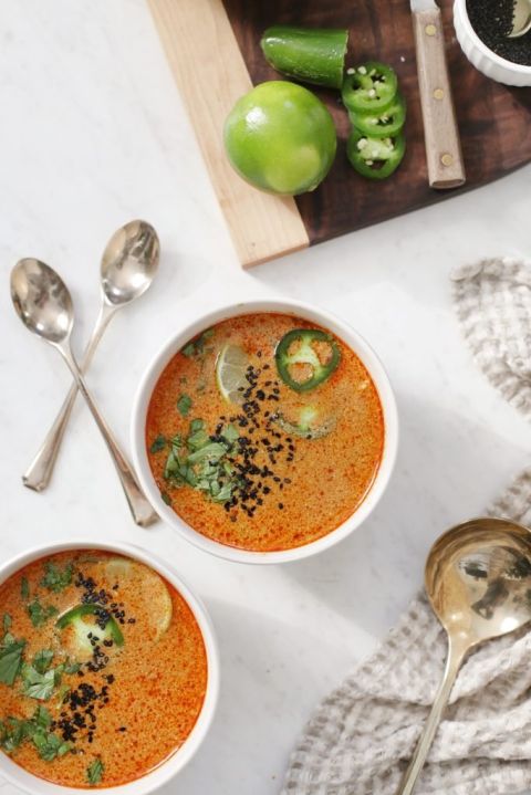 overhead shot of spicy thai peanut soup in bowls with spoons laying beside them