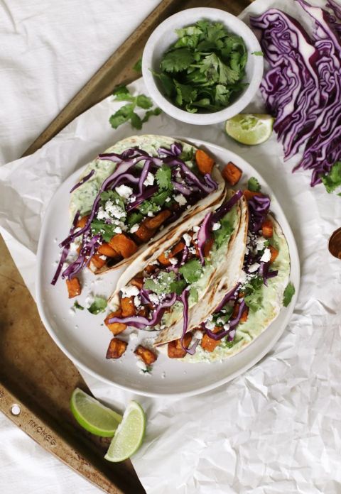 three tacos on a plate surrounded by raw ingredients