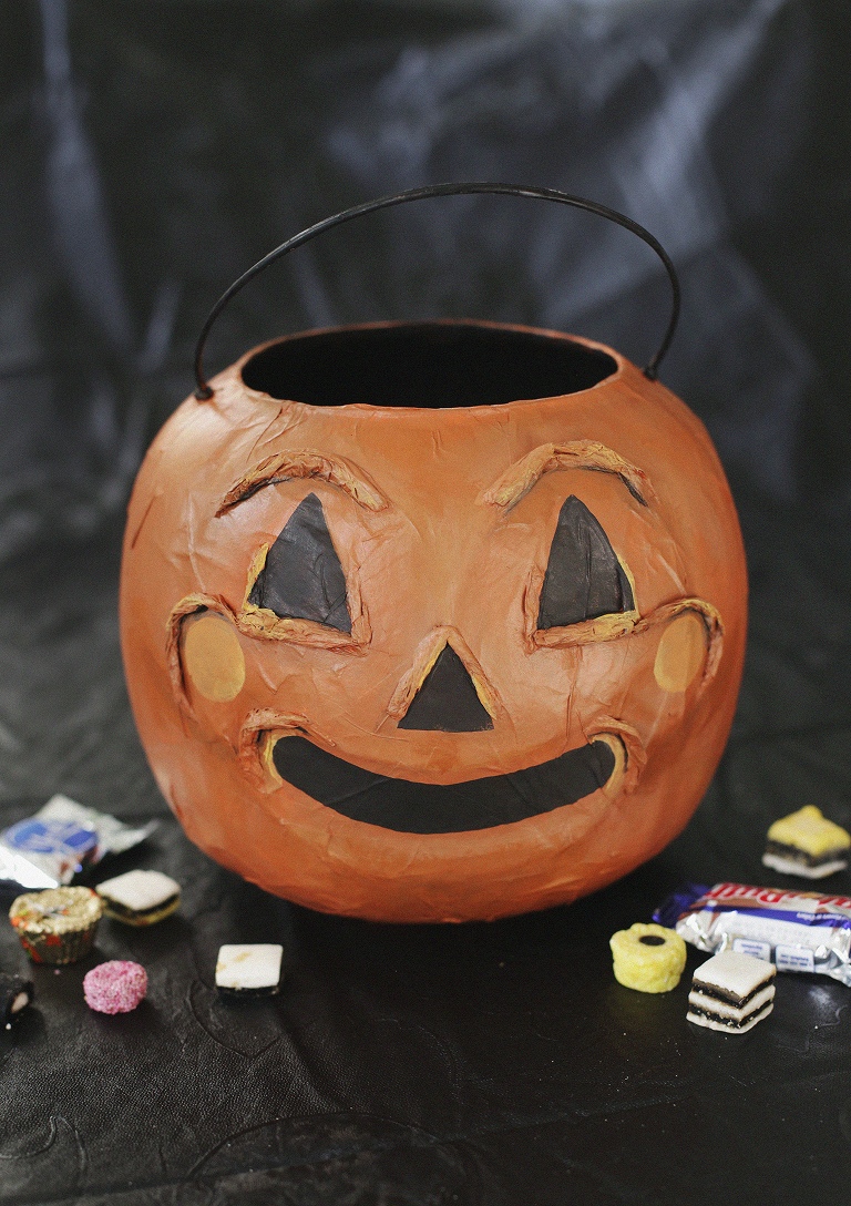 pumpkin bucket surrounded by candy on black backdrop