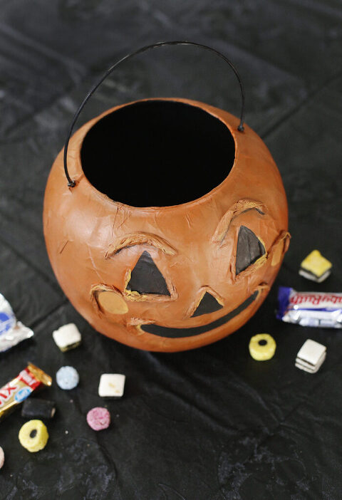 overhead shot of vintage-inspired pumpkin shaped treat bucket with candy surrounding it