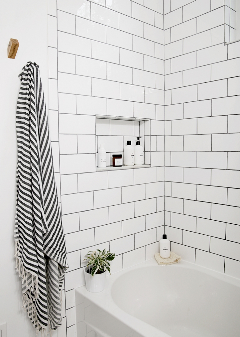 subway tile shower walls with shelf with shampoo bottles