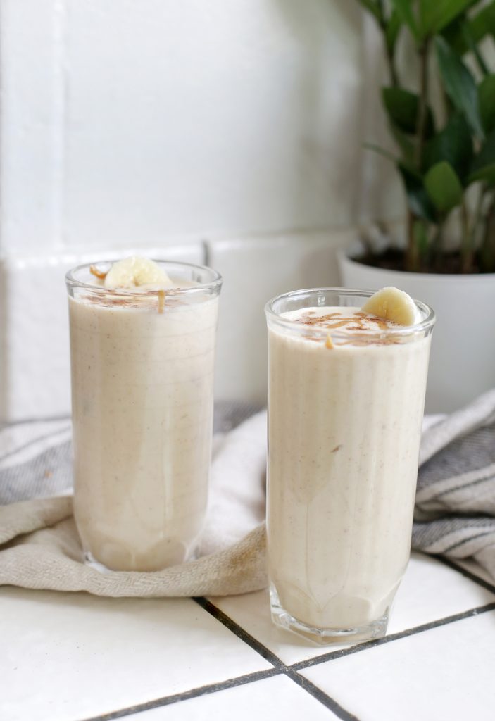 two cups full of smoothie on white counter with kitchen towel