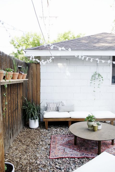 patio chair laid down next to white wall with round table in outdoor space