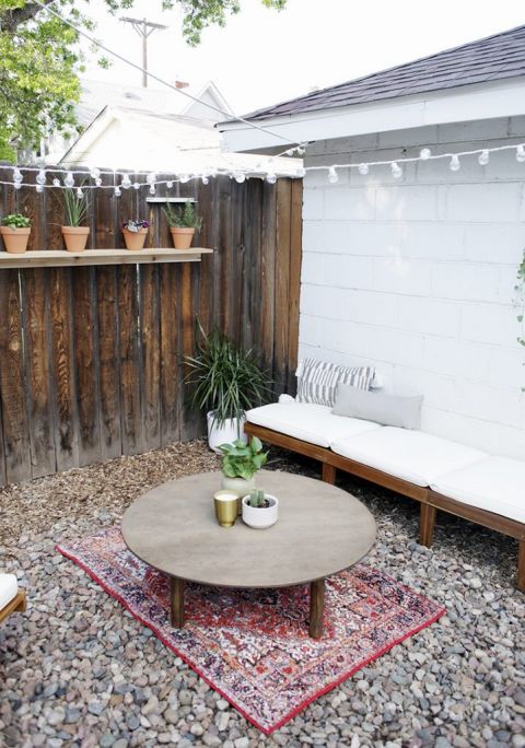 patio chair laid down next to white wall with round table in outdoor space