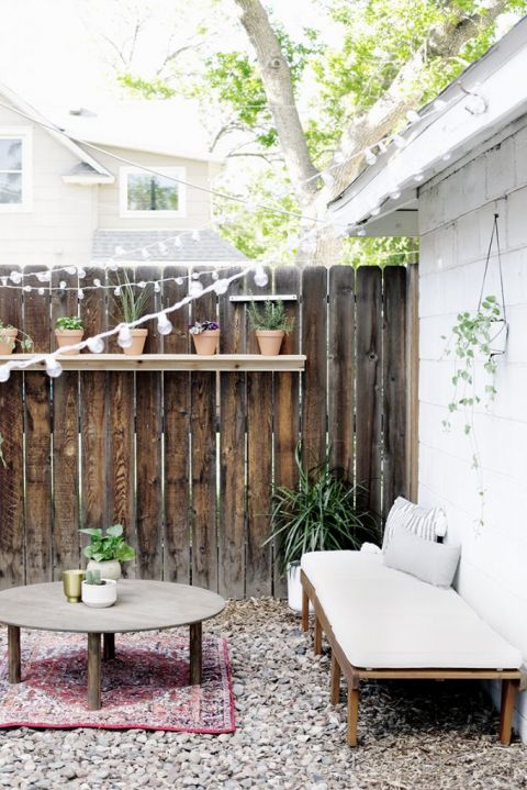 patio chair laid down next to white wall with round table in outdoor space