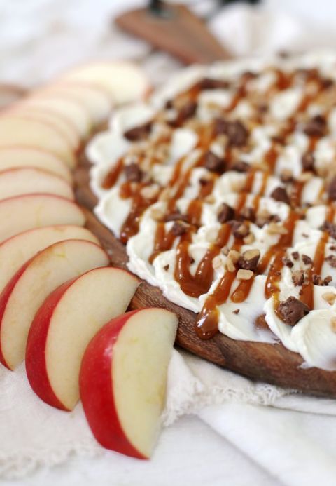 close up of cream cheese and caramel on cutting board surrounded by apple slices