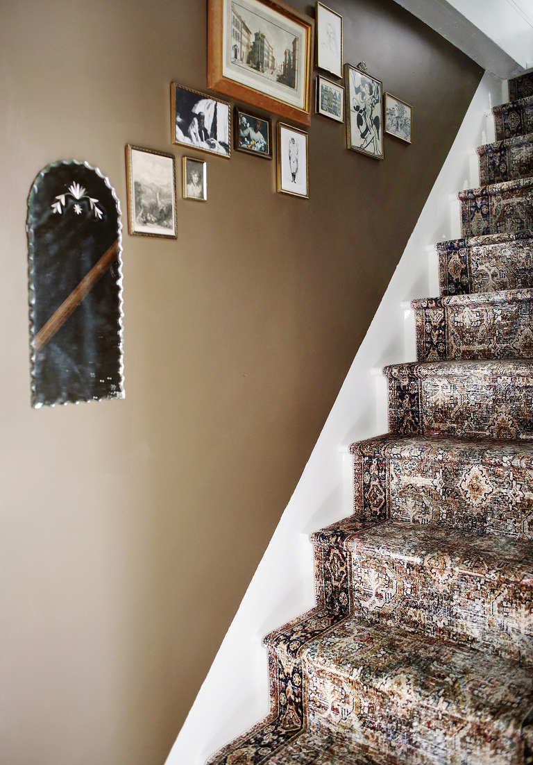 stair runner going up white and brown stairs with vintage frames and mirror on wall