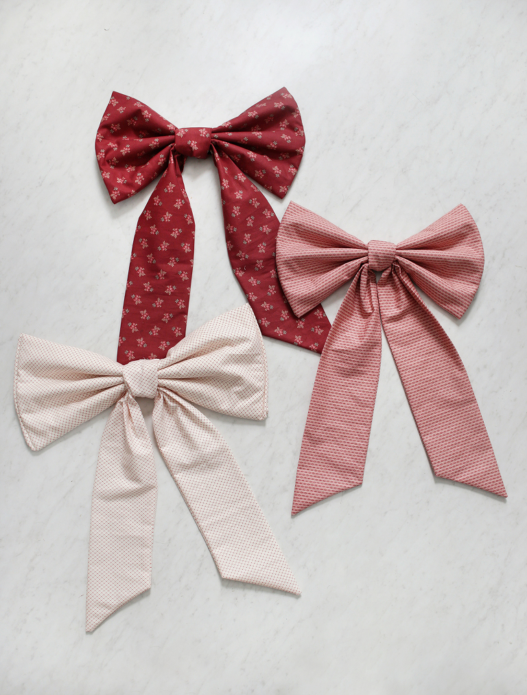 three large fabric bows laid on white marble