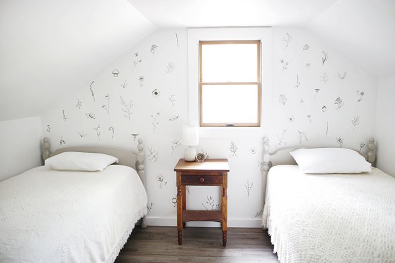 two twin beds in white room with painted floral accent wall