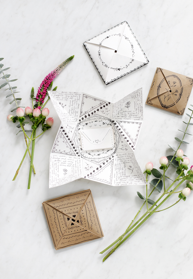 origami paper card opened surrounded by other cards and pink flowers