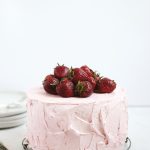 fresh strawberry cake with strawberries piled on top of cake on vintage cooling rack