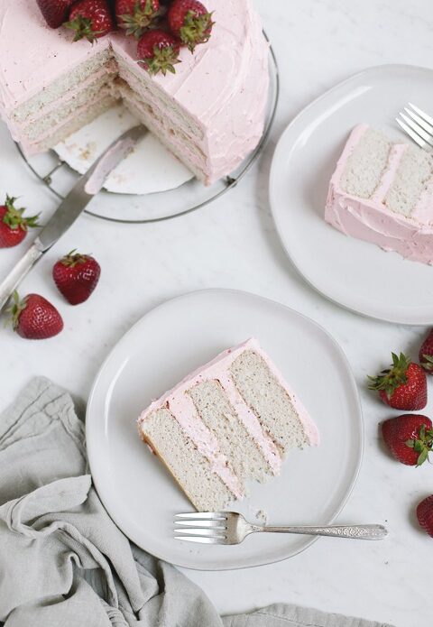 slice of cake with strawberries and whole cake sitting next to plate