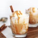 apple cider ice cream float in clear glass with cinnamon stick in it and caramel drizzle
