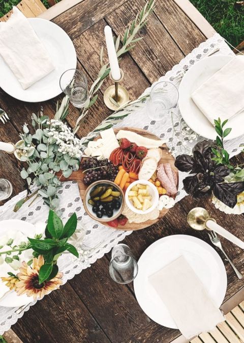 table setting with white runner and charcuterie board centerpiece with eucalyptus branches around it