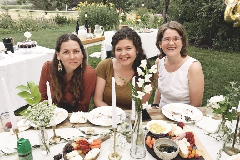 three white females sitting at table outdoors