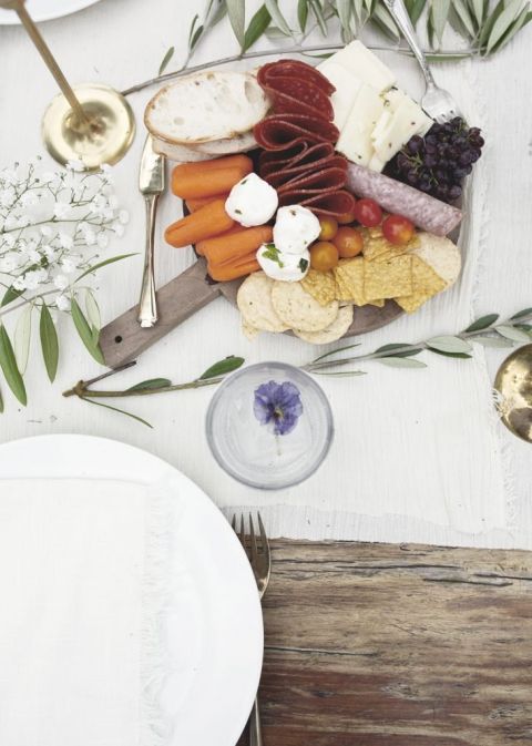 table setting with olive branches and small charcuterie board centerpiece