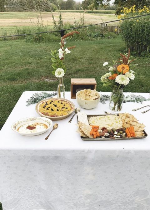 food table outdoors with food platters and flowers on table