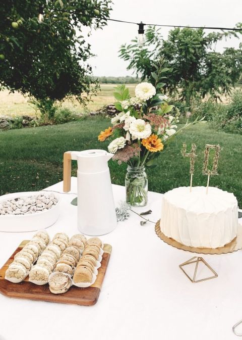 outdoor food table with cookies and cake and flowers on it