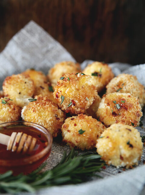 pile of baked goat cheese balls next to bowl of hot honey