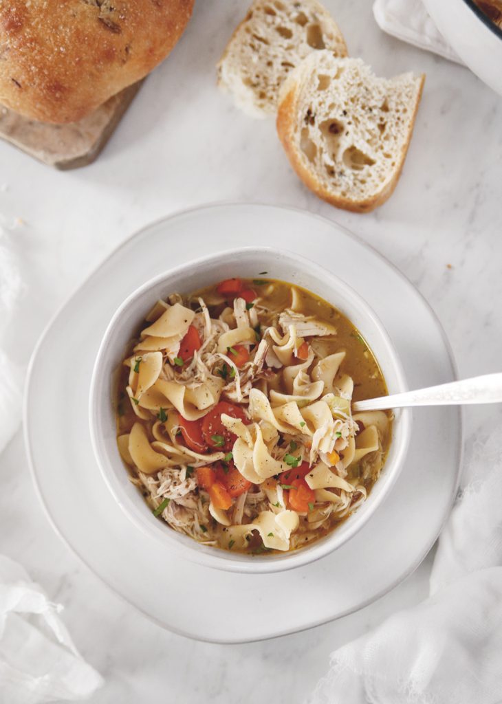 bowl of soup on table next to pieces of bread