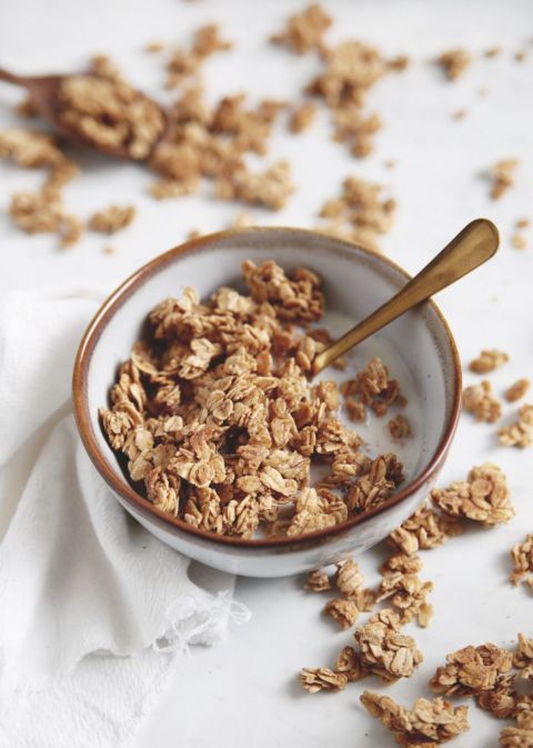 bowl of maple granola with milk and spoon in bowl with granola around bowl