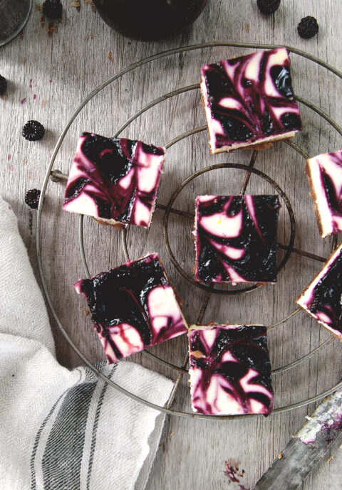 pieces woebegone raspberry cheesecake bars on round metal cooling rack