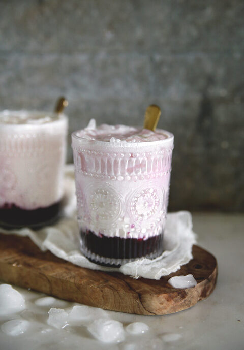 two glasses on wood cutting filled with black raspberry italian cream soda drink