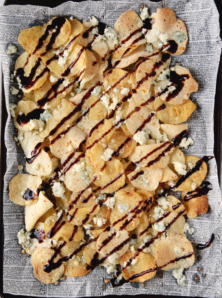 tray of potato chips on paper topped with blue cheese crumbles and drizzled with balsamic vinegar glaze