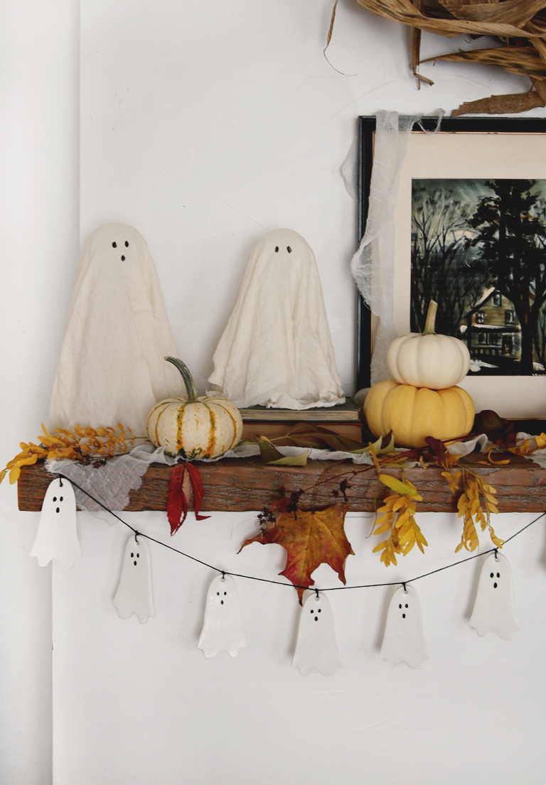 cheesecloths on wood mantel with clay ghost garland hanging below them