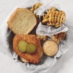 copycat Chick-fil-A sandwich with pickles on it next to waffle fries and dip