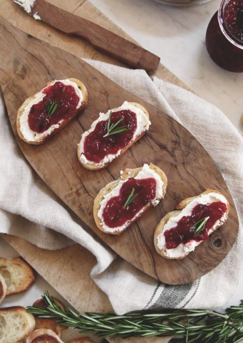 3 crostini appetizer with cranberries and feta on wood cutting board