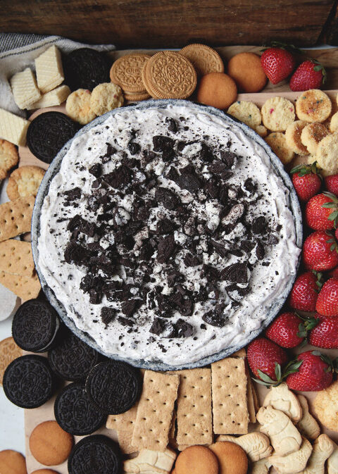 oreo dip in metal pan surrounded by cookies, crackers and strawberries to dip in it