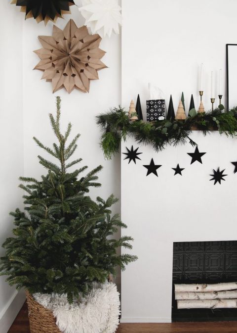 fireplace with greenery with small christmas tree next to