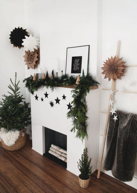 fireplace decorated with greenery garland, wood christmas tree and black 3D cardboard stars