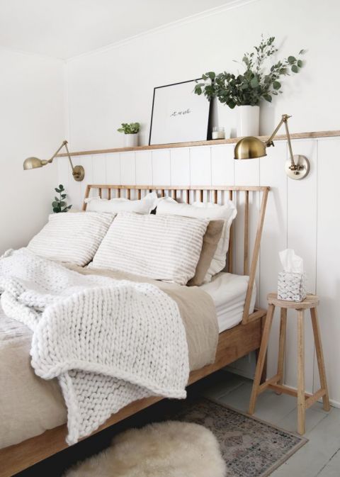 wood bed with white knit blanket on it with a stool next to bed