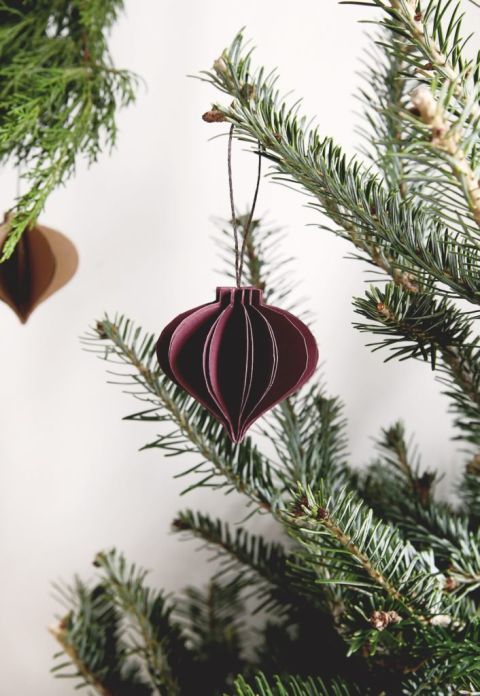 pine branches with maroon 3D paper ornament hanging from it