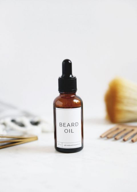 bottle of beard oil sitting by comb and towel