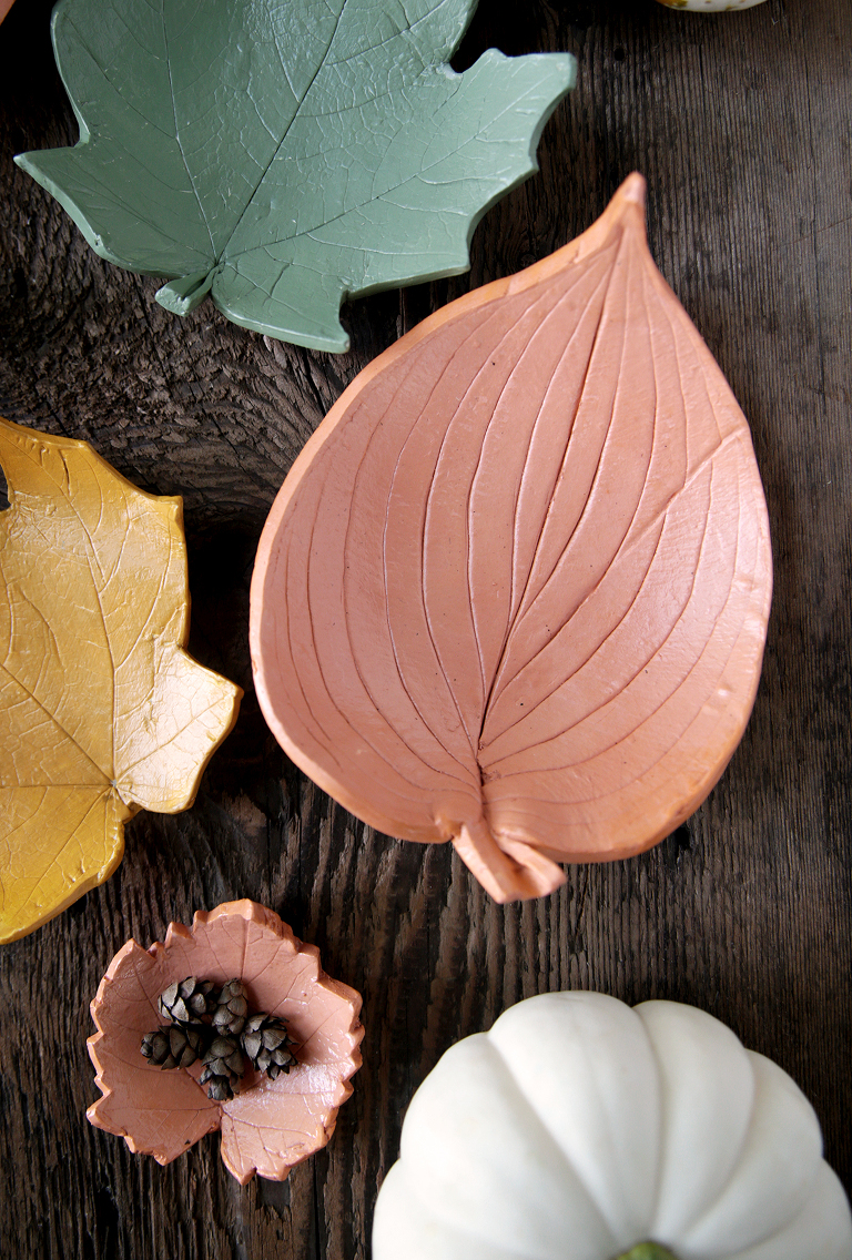 terracotta large clay leaf bowl sitting on wood with other clay leaves and pumpkin