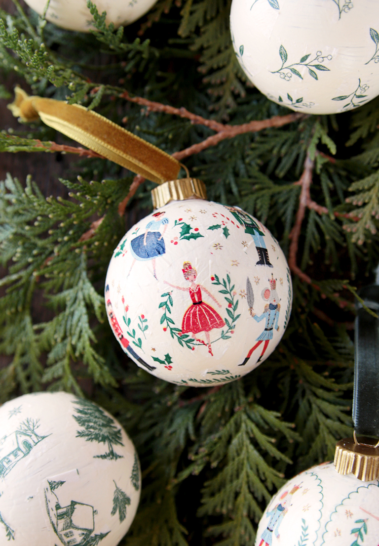 nutcracker decoupage ornament with gold ribbon laying christmas greens