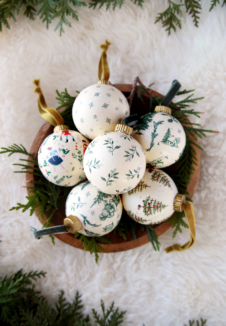 wood bowl with six decoupage ornaments in it on white sheepskin rug