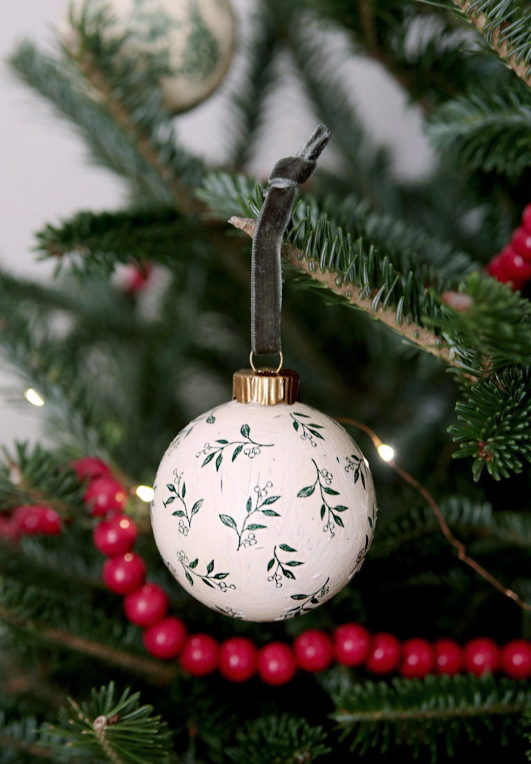 green and white floral decoupage ornament hanging on christmas tree