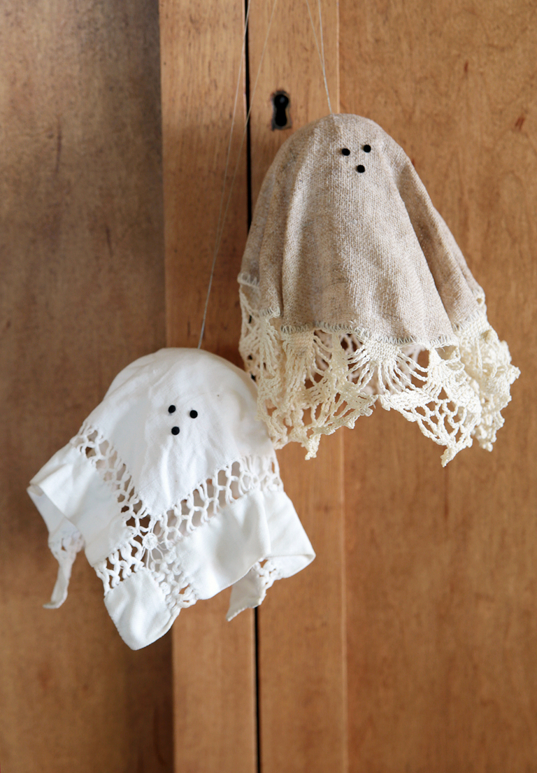 two small lace doily ghosts hanging on wood cabinet