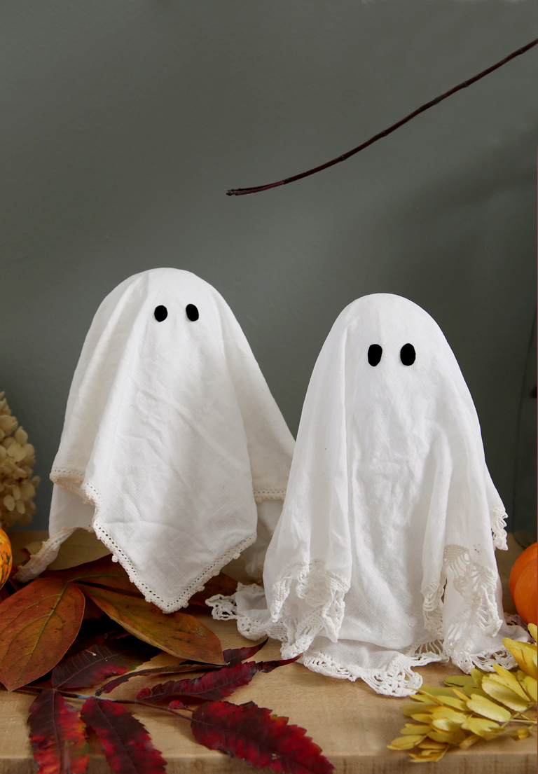 lace doily ghosts on wood shelf with fall leaves around them