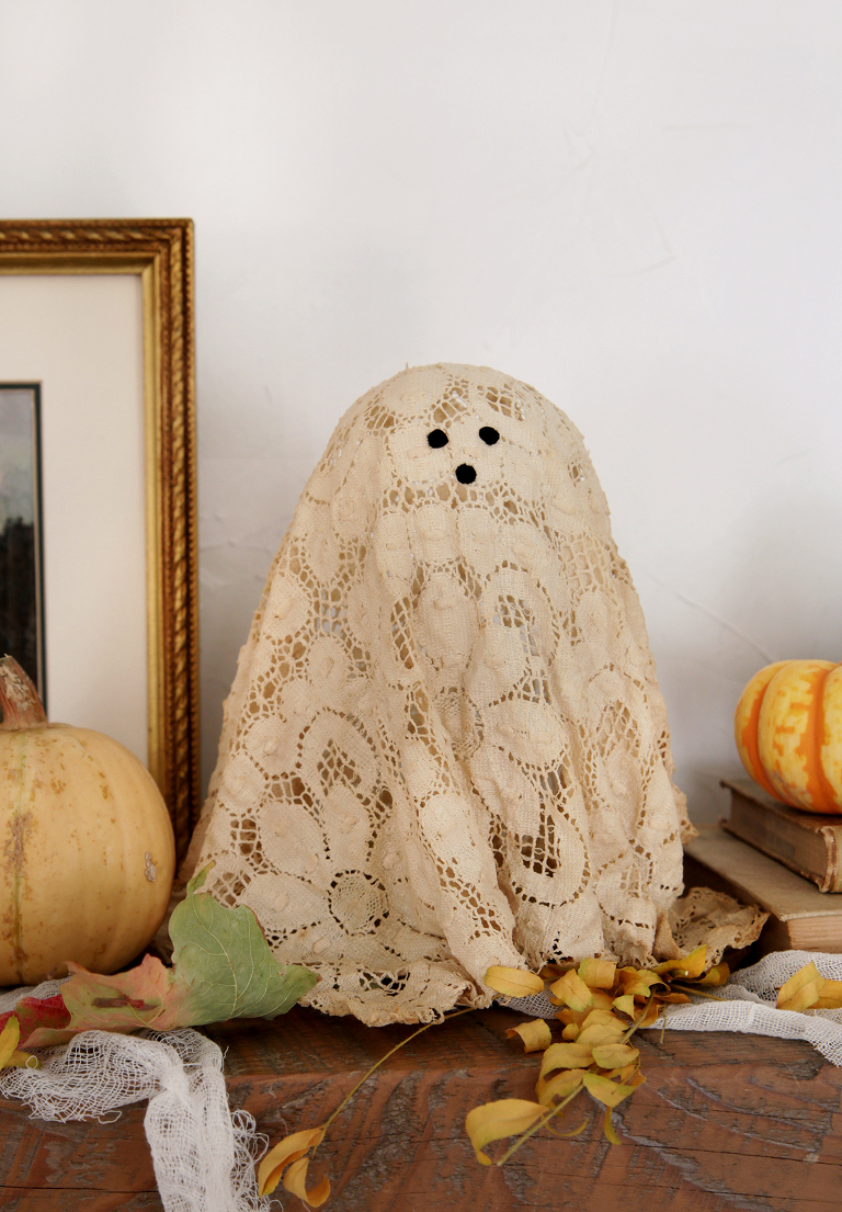 lace doily ghost on wood mantel with leaves and pumpkins around it