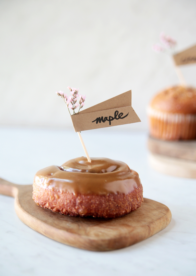 maple cinnamon roll on cutting board with floral toothpick food label stuck on top of roll