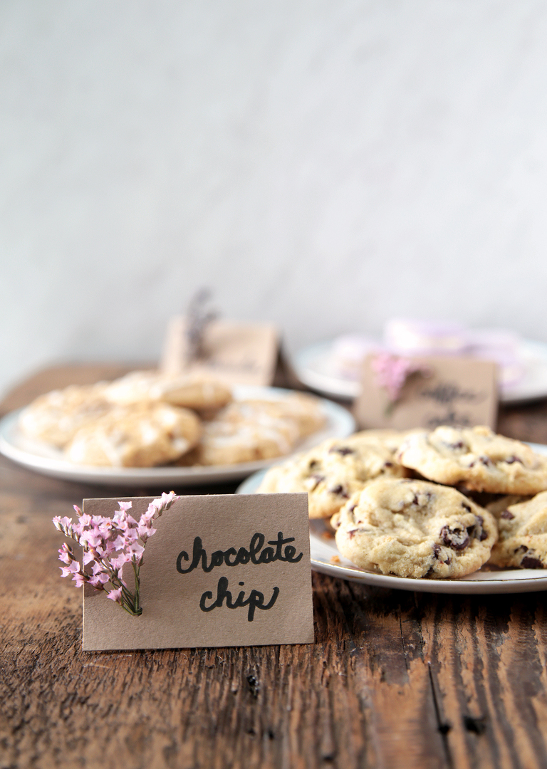 plate of chocolate chip cookies on wood board with DIY floral food label next to plate