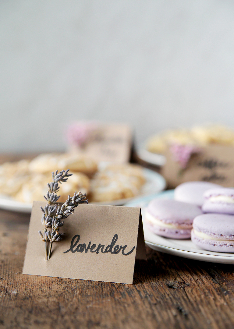 plate of lavender macarons with floral food label next to plate of cookies