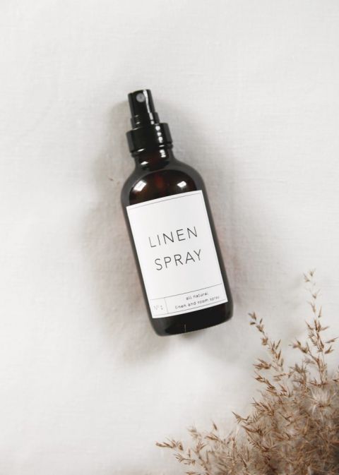 bottle of linen spray on white linen with dried grass