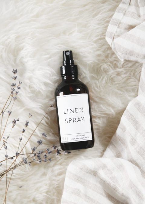 bottle of diy linen spray with label on white rug with dried lavender